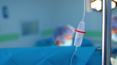 Satış tezgahının içinde şeffaf sıvı damlıyor. Kapatın. Ameliyathanede serum damlatılıyor. Doktorlar bulanık arkaplanda çalışır.