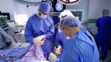 Erkek doktor, hastanın kafasına cerrahi sonda tutuyor. Nöroşirürji ekibi iyi donanımlı bir ameliyathanede nöroşirürji bölümünde çalışıyor..