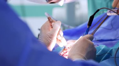 Beyaz lateks eldivenli doktorun elinde iki tıbbi alet var. Asistanı şırıngadan sıvı püskürtüyor. Kapat..