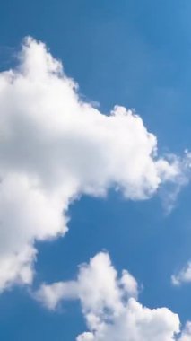 Gökte uçuşan pamuk gibi yumuşak bulutlar. Parlak güneş bulutları aydınlatıyor. Düşük açı. Zaman ayarlı. Dikey video