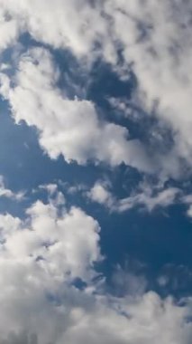 Atmosferde beyaz bulutlar birikiyor. Güneş yukarıdan yumuşak bulutları aydınlatıyor. Düşük açı. Zaman ayarlı. Dikey video