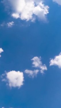 Yumuşak pamuk bulutları atmosferde hızla şekil değiştiriyor. Düşük perspektiften bulutlu yaz gökyüzü. Zaman ayarlı. Dikey video