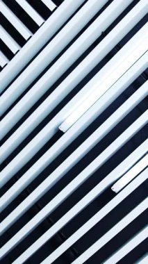 Tavanda uzun gün ışığı lambaları. Aydınlatma ekipmanına paralel beyaz kalaslar. Dikey video