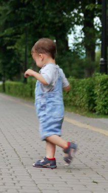 Parkta daireler çizen mutlu beyaz çocuk. Sağlıklı, aktif bir çocuk yazın dışarıda eğleniyor. Dikey video
