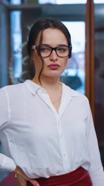 Ciddi genç bir kadın otele girdi ve resepsiyon bekliyor. İş kadını. İş kadını. Gözlüklü ve beyaz gömlekli Womnan. Dikey video