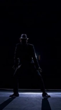 Karanlıkta sahnede kostümlü son sınıf öğrencisi. Tiyatrodaki gösteri sırasında sahnede dans eden şapkalı aktif bir adam. Dikey video