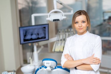 Modern klinikte çalışan bir dişçi. Çağdaş bir klinikte, uzman ve özenli hastalara yardım etmeye hazır bir diş hekimi kendine güvenir..