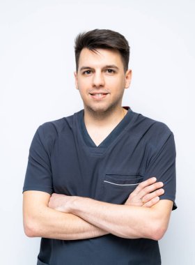 Önlüklerde kendine güveni tam bir profesyonel. Koyu renk önlüklü bir adam kollarını kavuşturmuş, parlak ve tarafsız bir ortamda gülümsüyor, profesyonellik taslıyor..