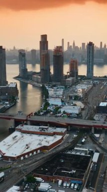 Muhteşem gökdelenleri olan ünlü New York şehri. İHA görüntüleri nehrin üzerinde bir köprüyle çevre yoluna yaklaşıyor. Dikey video