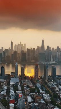 Güneş batarken Manhattan 'da. New York silueti turuncu bulutların altında. Üst Manzara. Dikey video