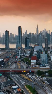 New York şehri güzel bir nehirle bölündü. Gün batımında metropolün manzarası. Şehrin üstündeki pembe gökyüzü. Dikey video