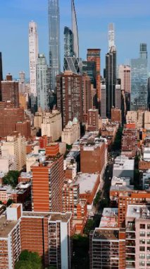 Parlak güneş New York 'un çok katlı binalarının ve gökdelenlerinin cephelerini aydınlatıyor. Metropolis şehir manzarası hava perspektifinden. Dikey video