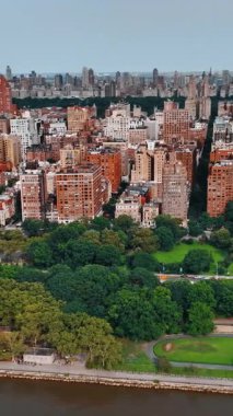New York 'un güzel yeşil rıhtımı boyunca insansız hava aracı görüntüleri. Çok katlı binaların gökdelenlere dönüştüğü bir manzara. Dikey video