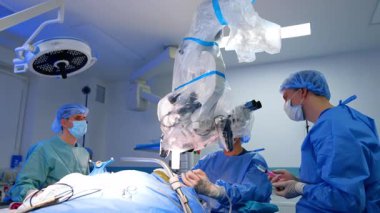 Cerrahlar ileri derecede ameliyat yapıyorlar. Ameliyat önlüğü ve maskeli cerrahlar gelişmiş teknoloji ve aletlerle karmaşık bir operasyon gerçekleştiriyorlar..