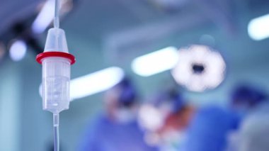 Damar yolu açık cerrahi müdahale. Tıbbi personel steril bir ortamda işlem yaparken cerrahi bir odada serum serumu görünür..