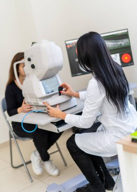 Klinikte göz muayenesi. Bir sağlık uzmanı ileri seviye tanı ekipmanları kullanarak bir hastaya göz muayenesi yapar..