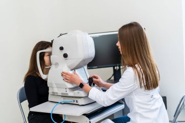 Göz muayenesi optometrist tarafından yapıldı. Bir profesyonel, modern bir klinik ortamında gelişmiş ekipman kullanan bir hasta için göz muayenesi yapıyor..