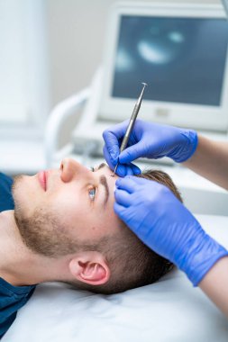 Modern kaş şekillendirme oturumu. Bir adam kaş şeklini kuaförde alır. Profesyonel biri görünüşünü geliştirmek için belirli teknikler uygular..