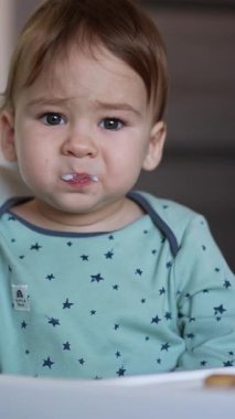 Yemek yiyen küçük şirin bir çocuğun portresi. Mutlu çocuk kahvaltı yapıyor. Dikey video