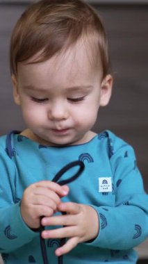 Yerde oynayan küçük şirin bir çocuk. Küçük komik çocuk öğreniyor. Dikey video