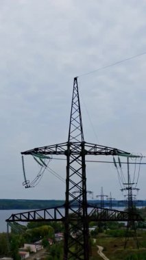 Mavi gökyüzünün altındaki elektrik direkleri. Elektrik tedarik etmek için yüksek voltaj iletim kuleleri. Dikey video