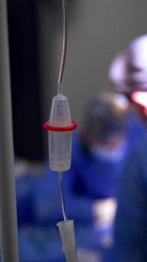 İçinde ilaç damlayan bir tezgah. Kapatın. Arka planda çalışan doktorların bulanık görüntüsü. Dikey video.