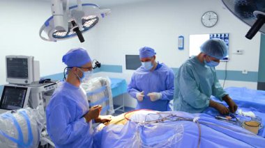 Modern ameliyathanede iki doktor ve asistan çalışıyor. Erkek hemşire cerrahi aletleri beyin cerrahlarına verir..
