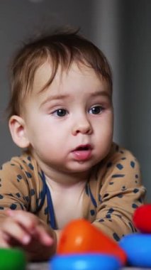 Küçük bir çocuk eğitici oyuncaklarla oynar. Sevimli bir çocuğun oynadığı renkli bir oyuncak. Dikey video