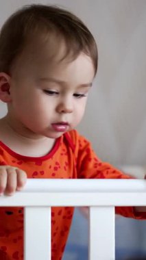 Yatakta duran sevimli çocuk. Yeni doğmuş sevimli çocuk bir ağla oynuyor. Dikey video