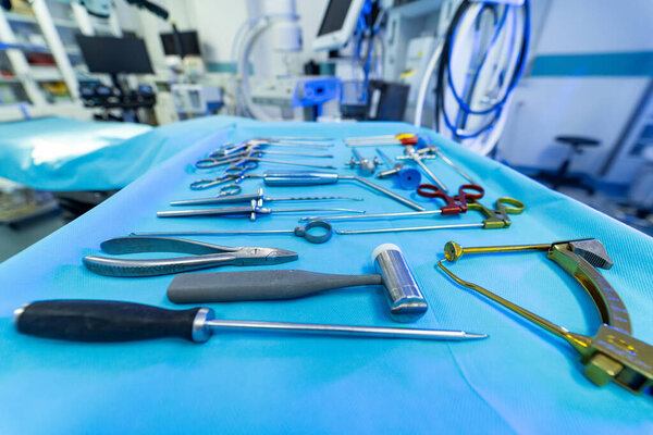 Key tools for neurosurgery. A variety of surgical instruments are organized on a sterile draped table in an operating room ready for neurosurgery.