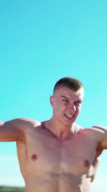 Spor fitness sporu. Yoğunlaşmış genç sporcu dışarıda, dambıllarla üst kollar için egzersiz yapıyor.