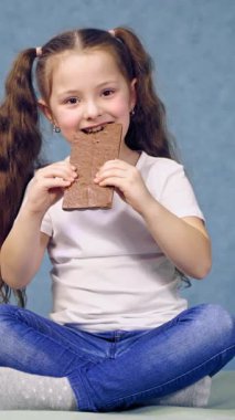 Çikolata yiyen kız. Masada oturan ve çikolata yiyen kız.