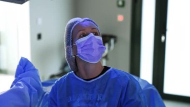 Maskeli kadın cerrah monitöre odaklanmış. Jinekolojik ameliyat yapan doktorun portresi..