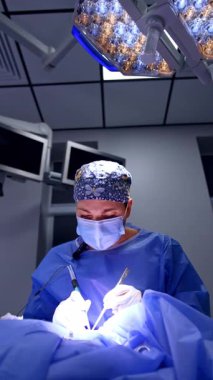 Profesyonel kadın cerrah iki elle ameliyat aletleri tutuyor. Ameliyathanede çalışan bir doktorun portresi. Dikey video.