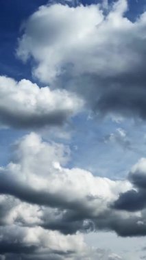 Yumuşak kümülüs bulutları rüzgarla hareket etti. Atmosferde oluşan ağır bulutların düşük açılı görüntüsü. Zaman ayarlı. Dikey video.