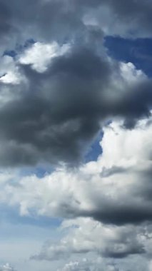 Gri ağır bulutlar atmosferde birikiyor. Göz kamaştırıcı bulutlarla dolu güzel gökyüzüne alçak açılı bir bakış. Zaman ayarlı. Dikey video.