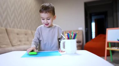 Neşeli erkek bebek toz bezi ve kağıt parçalarıyla oynuyor. Güzel çocuk evde eğleniyor..