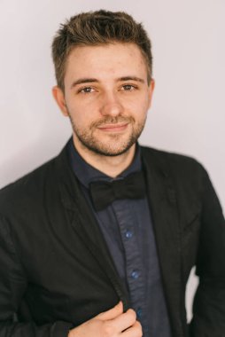 Takım elbiseli kendine güvenen genç adam. Siyah smokinli ve papyonlu bir adam, sakin ve kendinden emin bir tavır sergiliyor..