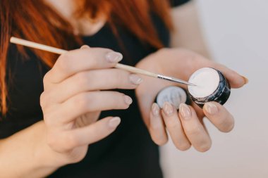 Makyajı nazikçe sürüyorum. Bir insan bir elinde makyaj kabı tutarken, bir fırça kullanarak, hassasiyete odaklanarak makyaj yapar..