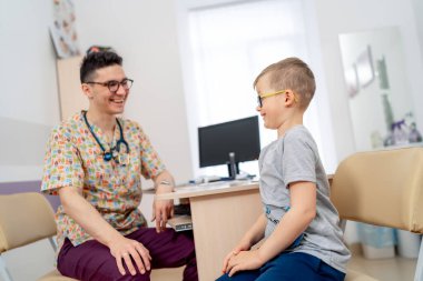 Doktor ve genç bir hasta. Bir sağlık uzmanı, modern bir tıbbi tesiste sağlık kontrolü sırasında bir çocukla temas kurar..