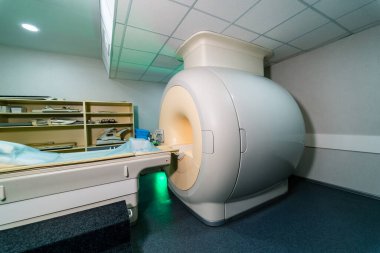 MR makinesi tıbbi muayene odasında. Büyük bir MRI makinesi temiz bir tıbbi muayene odasına yerleştiriliyor. Atmosfer klinik ve hasta kullanımı için hazır..