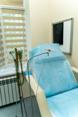 Ekipmanlarla birlikte tıbbi muayene odası. Parlak tıbbi muayene odasında hasta koltuğu, izleme cihazları ve pencereden gelen yumuşak doğal ışık var..