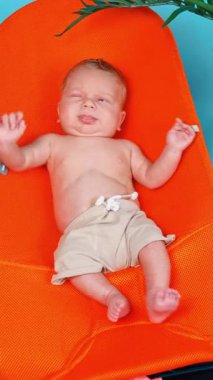 Bebek koltuğunda uzanmış küçük beyaz bir bebek ağlamaya başlıyor. Yeni doğan çocuk plajda dinleniyor. Dikey video