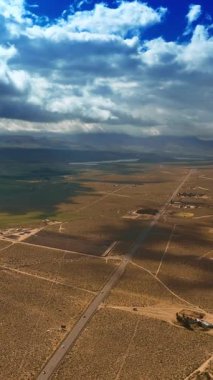 Çölün üzerinde asılı fantastik bulutlar ve karaya gölgeler. Havadan bakıldığında Nevada çölünün güzel manzarası. Dikey video