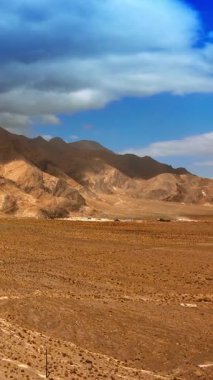 Çıplak dağlarla çevrili ıssız arazinin üzerinde yükseliyor. Nevada 'nın kuru ve sıcak manzarası. Tepenin üstünde dramatik bulutlar asılı. Dikey video