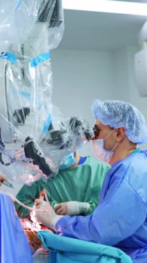 Kafkasyalı cerrah, mikroskop ameliyatına dikkatlice bakıyor. Profesyonel doktor portresi. Dikey video.