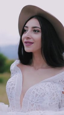 Dağda lüks ve mutlu bir gelin. Güzel manzaraya karşı düğün buketiyle yürüyen şık bir gelin.