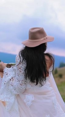 Gelin gelinlik içinde poz veriyor. Genç gelin dağda poz verirken mutlu görünüyor.