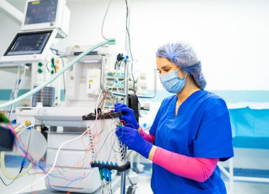 Ekipman kullanan bir tıp uzmanı. Mavi önlüklü bir sağlık çalışanı, gündüzleri hastane ortamında tıbbi ekipmanların ayarlanmasına odaklanır..