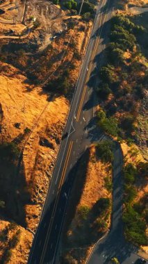 Dağlar ve göl arasında geçen otoyol. California çölündeki kayaların üstündeki insansız hava aracı görüntüleri. Dikey video